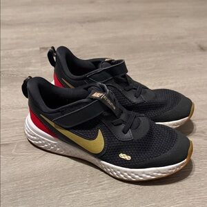 Nike Revolution Kids Black Sneakers with Gold Swoosh and Red Heel